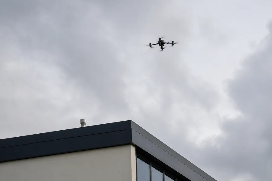 Survey drone above the roof edge of a commercial building
